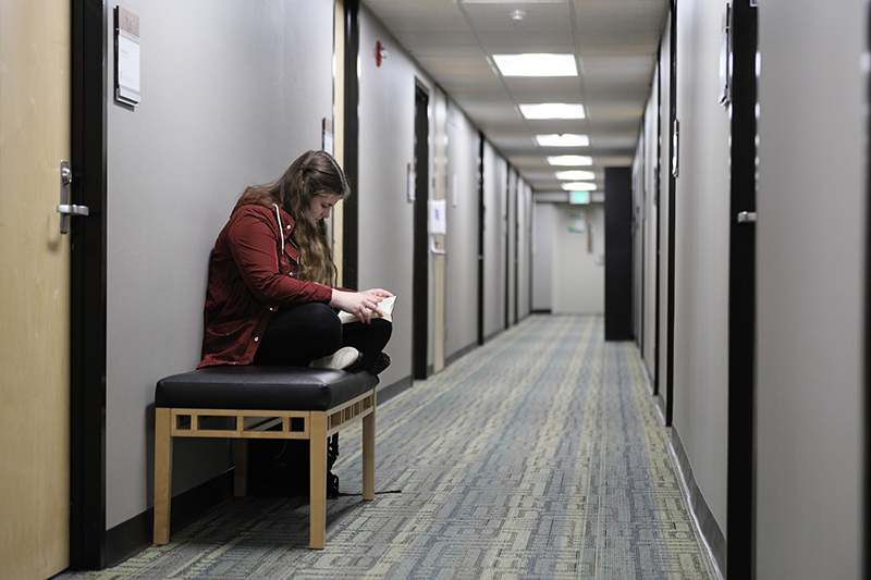 student sitting on a bench in hallway of Case
