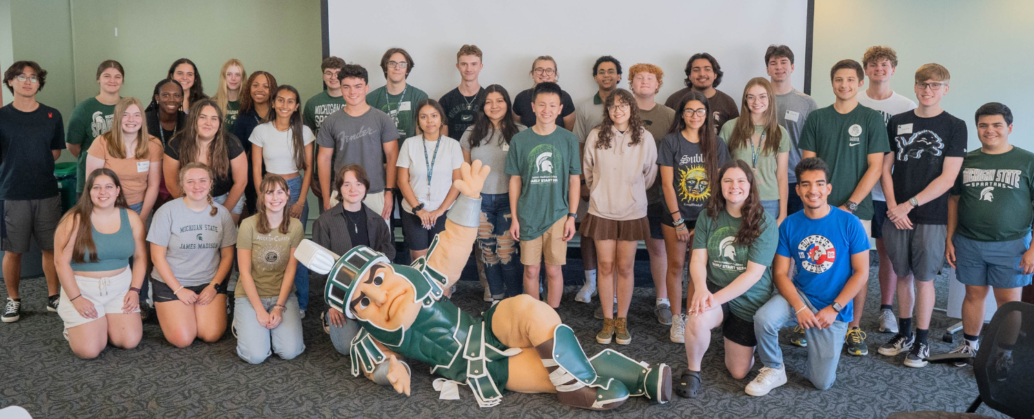 The 40 student participants stand in group with the Sparty mascot at the 2024 Welcome Lunch.