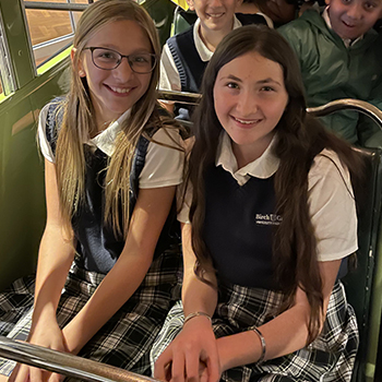 students seated on bus wearing uniforms