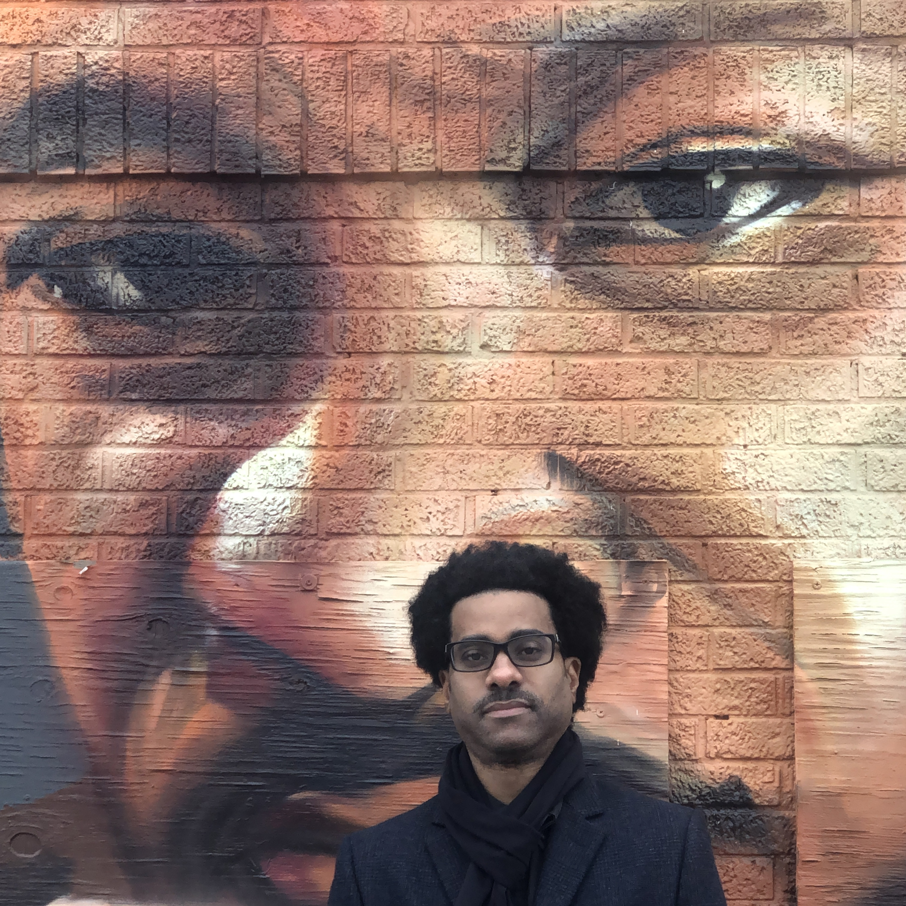 Dean Johnson stands in front of a mural of MLK Jr.