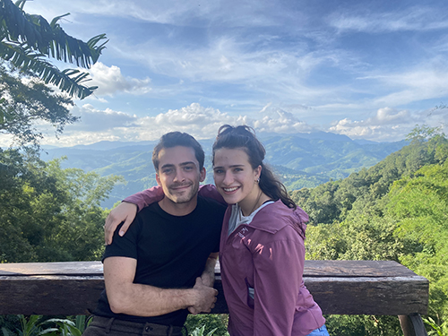 man and woman standing in front of a mountain overlook point